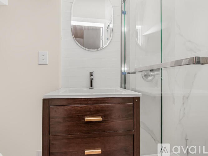 A bathroom vanity with a marble countertop and a round mirror above it.