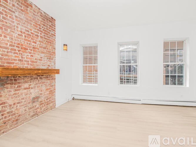A room with a brick wall and two windows.
