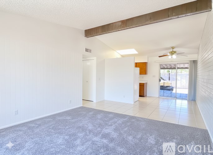 A spacious living room with a grey carpet and white walls.