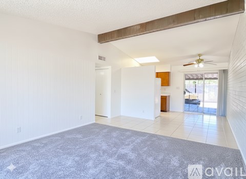 A spacious living room with a grey carpet and white walls.