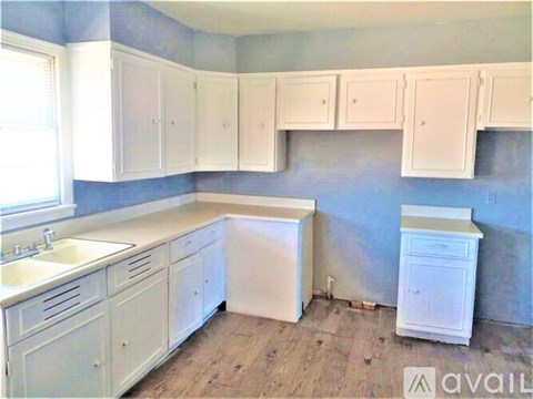 A kitchen with white cabinets and a wooden floor.