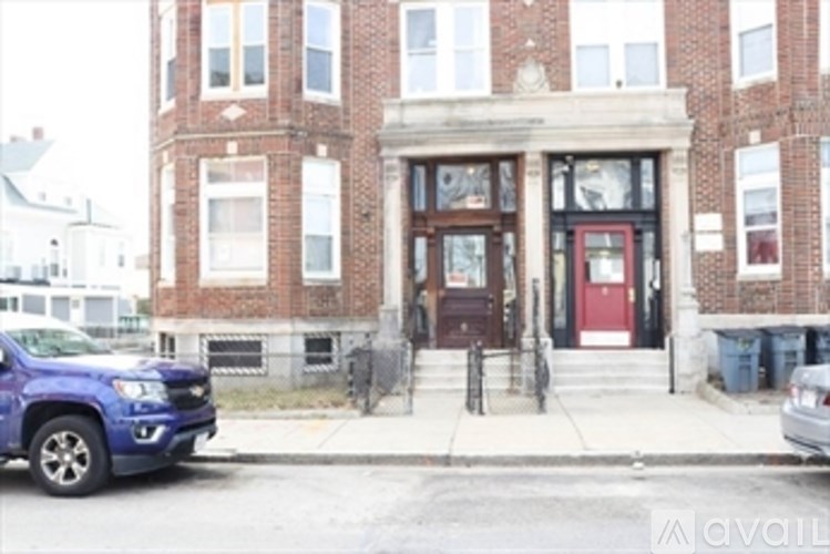 A blue truck is parked on the street in front of a brick building.