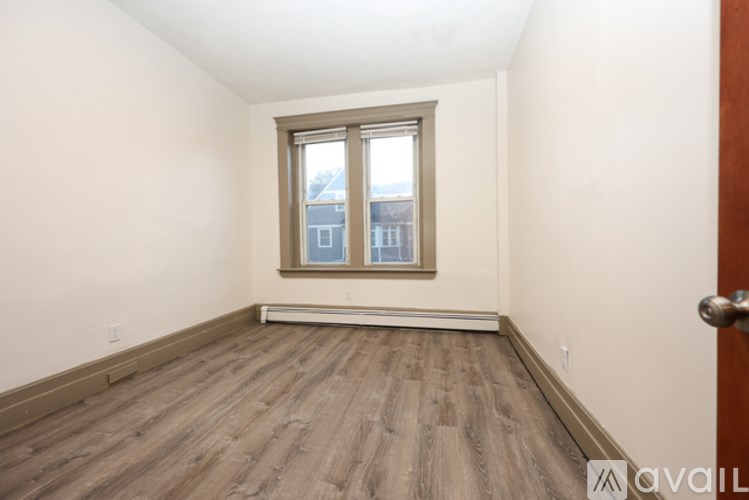 Two people are walking on a street in front of a red brick building.