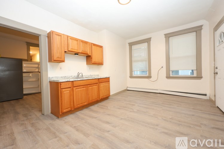 A window with a white frame and brown trim is in a room with a white wall and a wood floor.