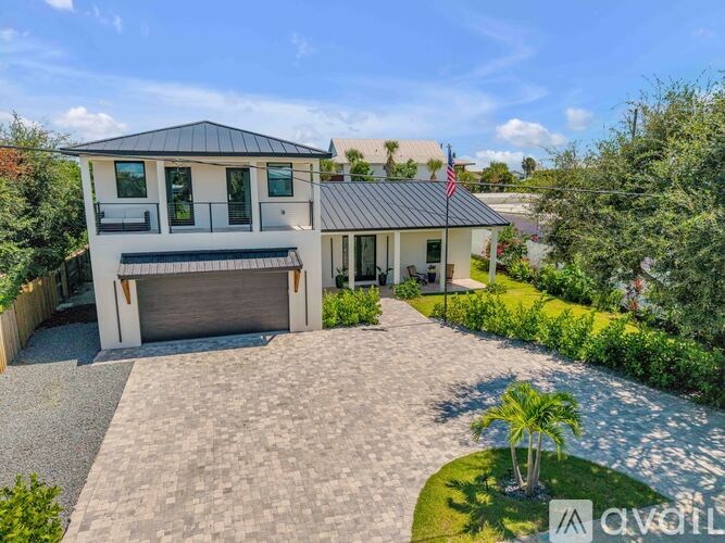 A modern house with a flag on the roof and a driveway leading to the garage.