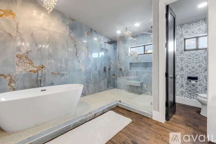 A bathroom with a marble wall and a white bathtub.