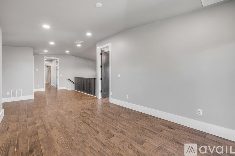 A spacious room with wooden flooring and white walls.