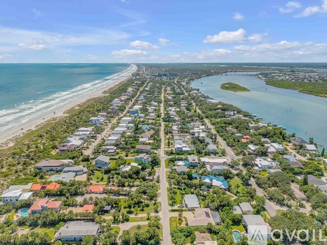 A bird's eye view of a residential area with houses, a beach, and a body of water.