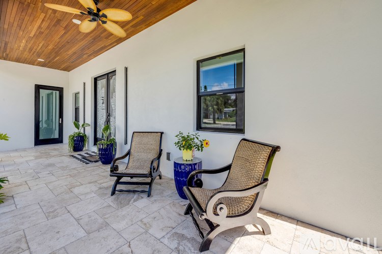 A patio with two chairs and a table with a plant on it.