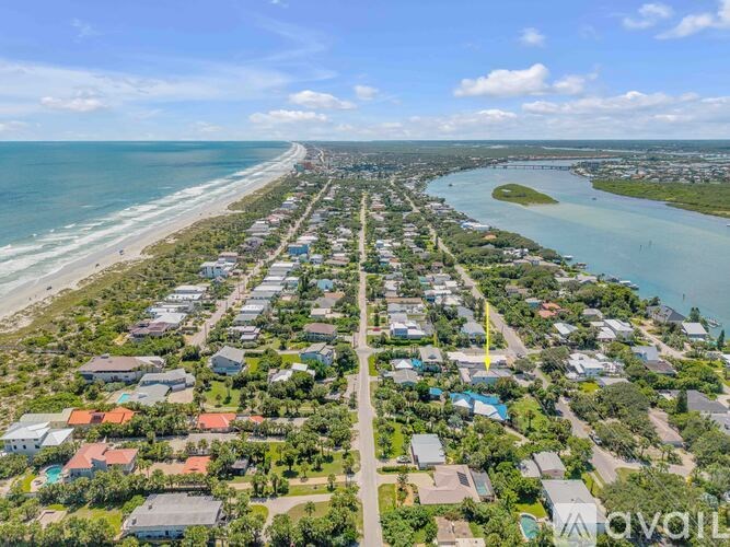 A bird's eye view of a residential area with houses, a beach, and a body of water.