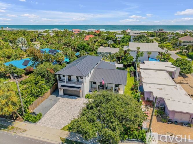 A bird's eye view of a house with a swimming pool and a beach in the background.