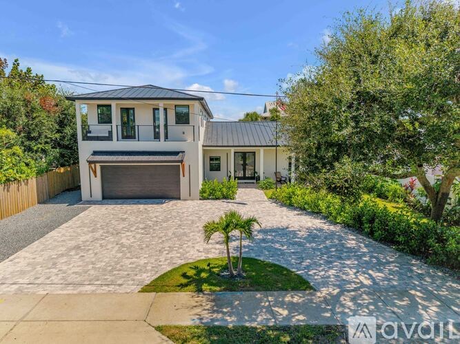 A modern house with a grey roof and a driveway leading to a garage.