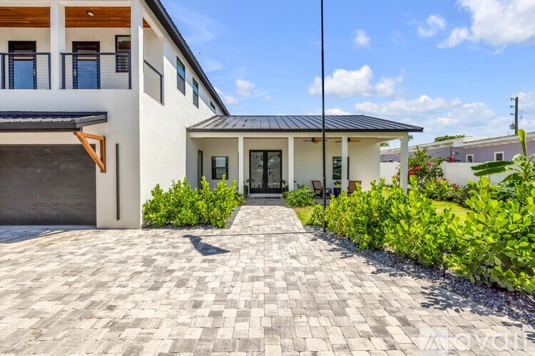 A modern house with a black roof and a grey tiled driveway.