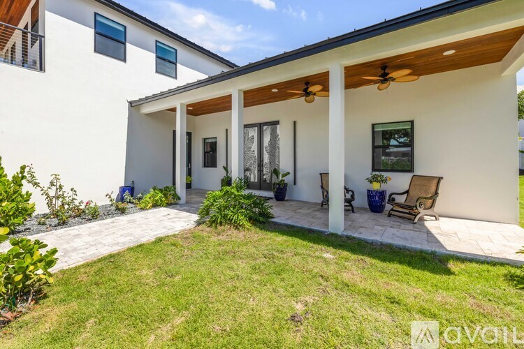 A white house with a covered patio and a lawn.
