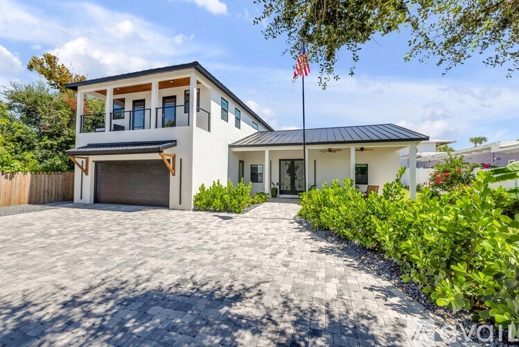 A house with a flag on a flagpole stands in front of a driveway.