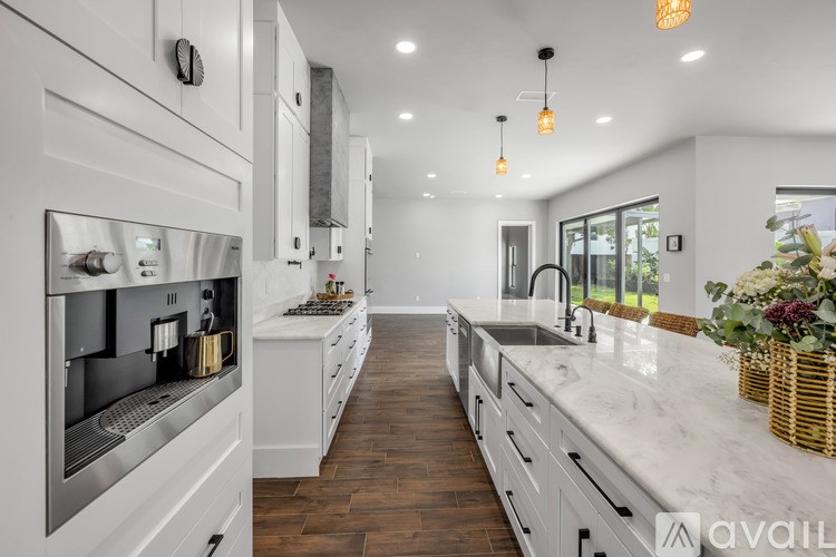 A modern kitchen with white cabinets and a marble countertop.
