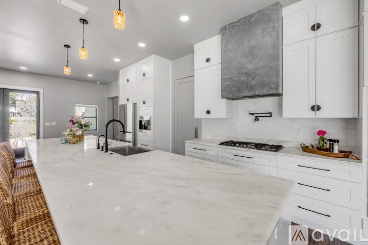 A modern kitchen with white cabinets and a marble countertop.