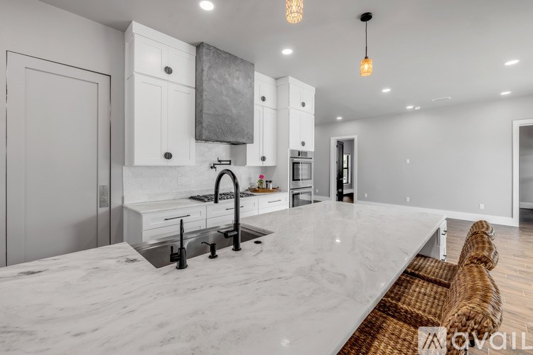 A modern kitchen with a marble countertop and stainless steel appliances.