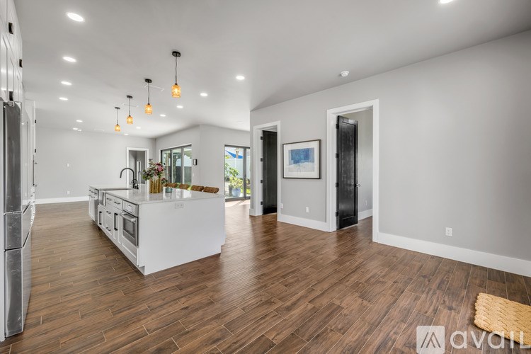 A modern kitchen with wooden floors and white appliances.
