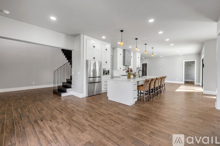 A spacious kitchen with wooden flooring and a dining area with chairs.