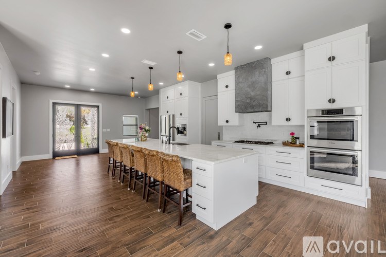 A modern kitchen with white cabinets and a wooden floor.