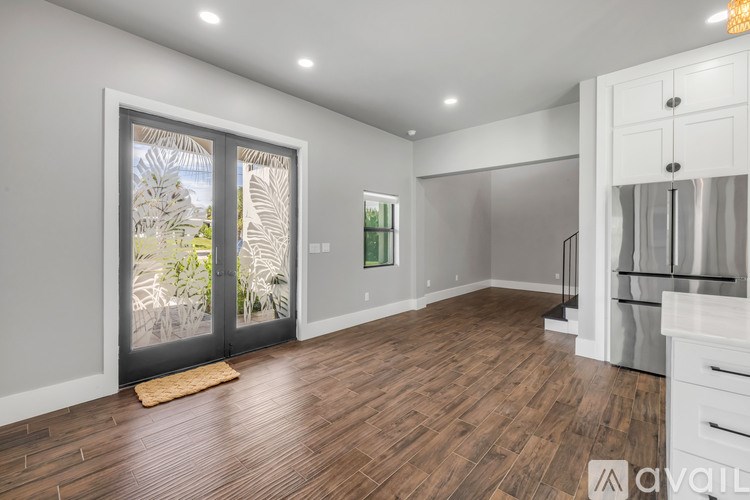 A room with wooden floors and a large window with a view of a garden.