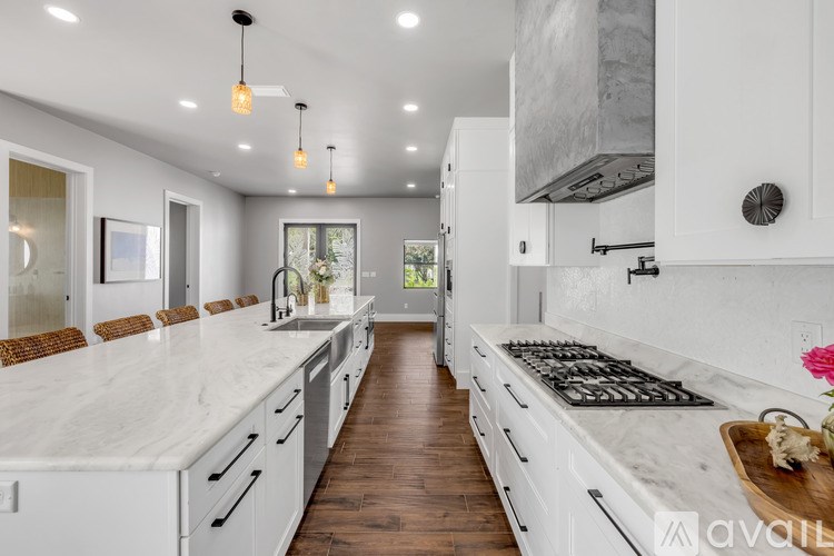 A modern kitchen with white cabinets and a marble countertop.