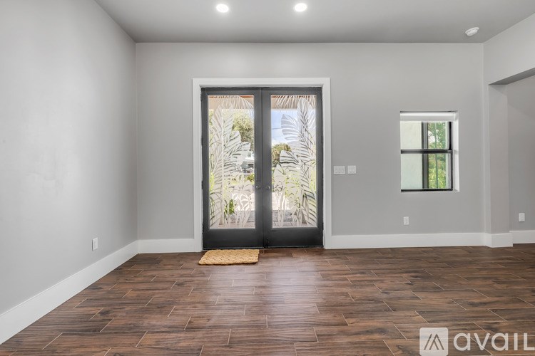 A room with a wooden floor and a glass door leading to a balcony.