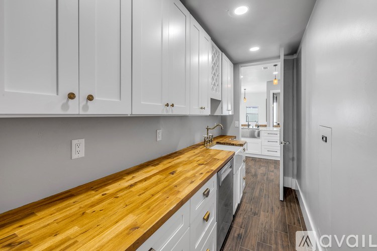 A kitchen with white cabinets and a wooden countertop.