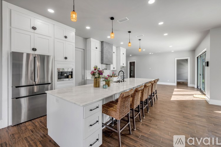 A modern kitchen with a long white island and stainless steel appliances.