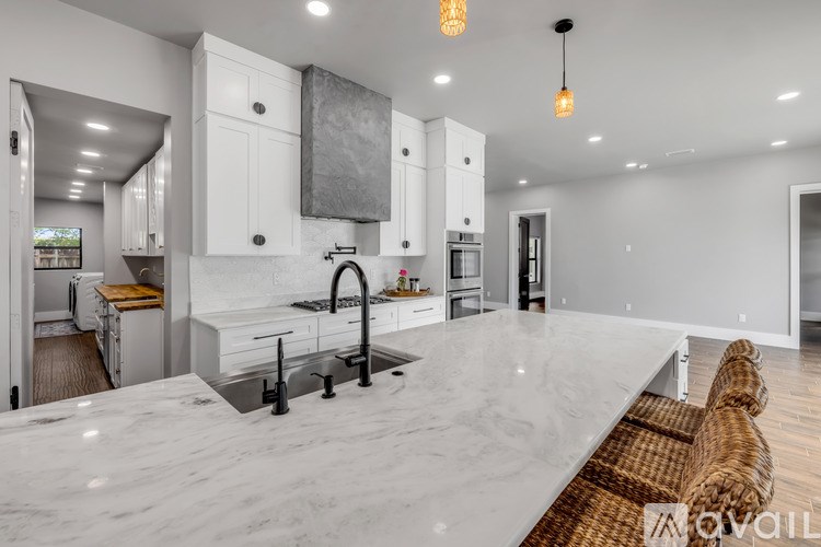 A modern kitchen with white cabinets and a marble countertop.