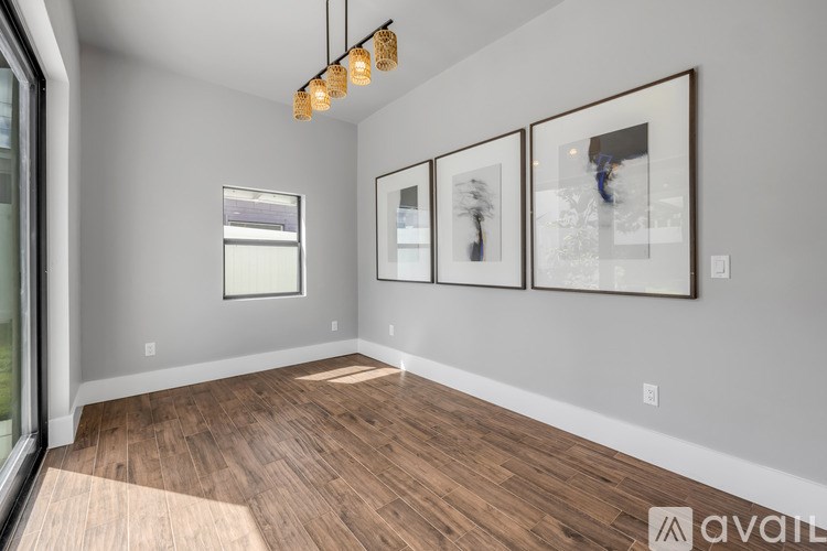 A room with wooden floors and three framed pictures on the wall.