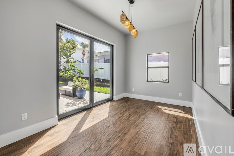 A room with wooden floors and a large window with a view of a garden.