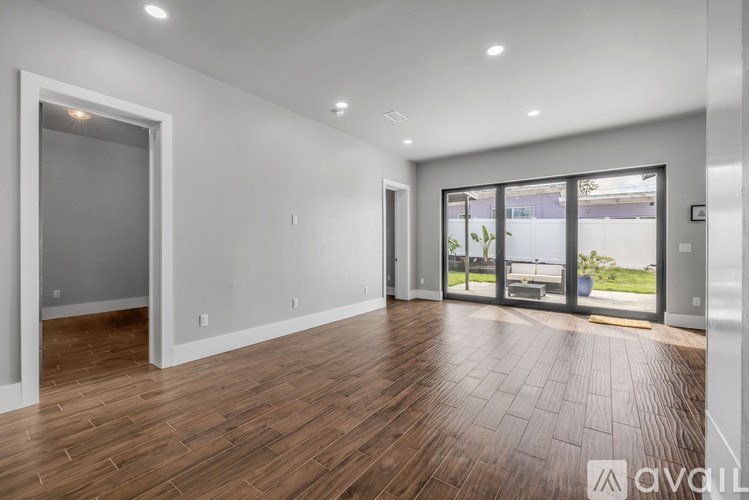 A spacious room with wooden flooring and a large window.