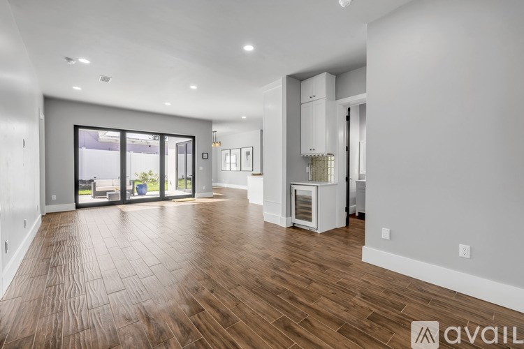A spacious living room with hardwood floors and a kitchen area in the background.