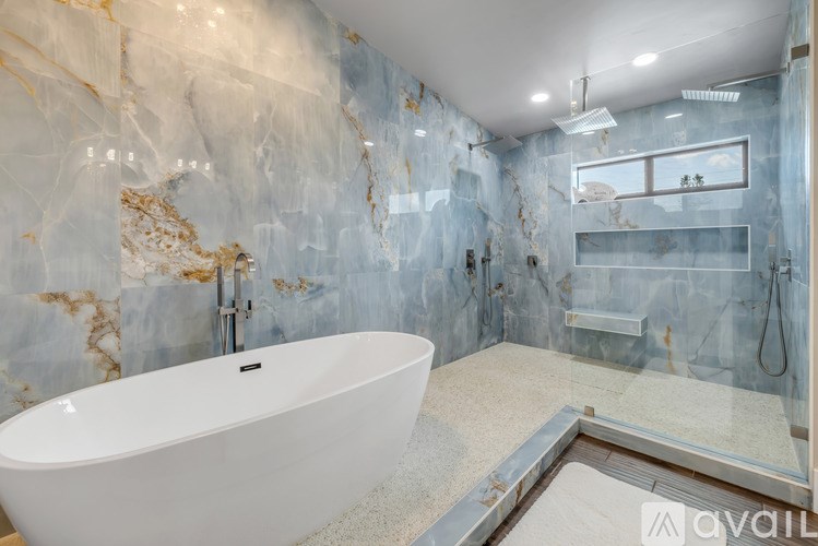 A modern bathroom with a marble wall and a white bathtub.