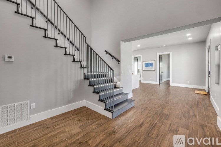 A spacious room with a staircase and wooden flooring.