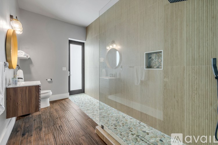 A bathroom with a wooden floor and a glass shower stall.