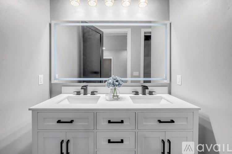 A bathroom with a vanity, sink, mirror, and lights.