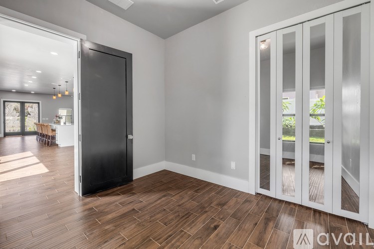 A room with a black door and wooden flooring.