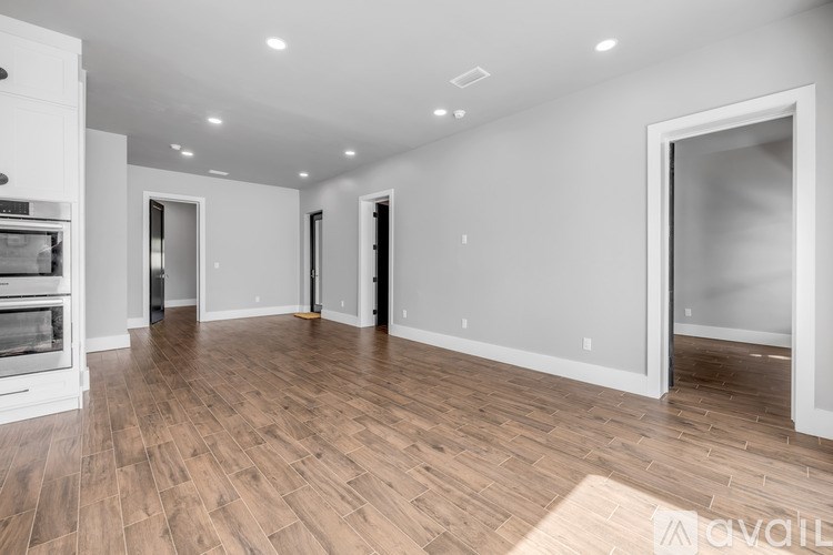 A spacious room with wooden flooring and white walls.