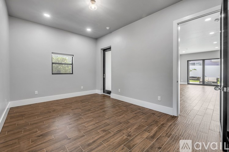 A spacious room with wooden flooring and a large window.