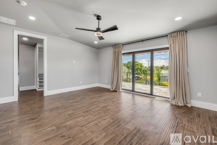 A spacious room with a ceiling fan and sliding glass doors.