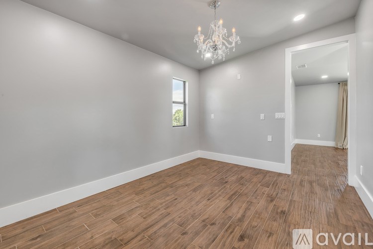 A room with wooden flooring and a chandelier.