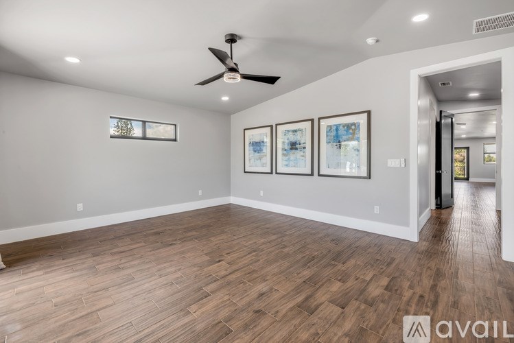 A room with a ceiling fan and three framed pictures on the wall.