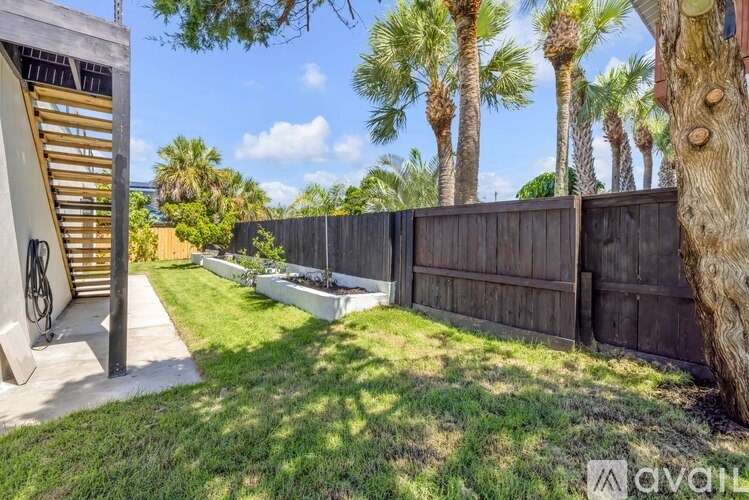 A backyard with a wooden fence and a tree trunk on the right side.