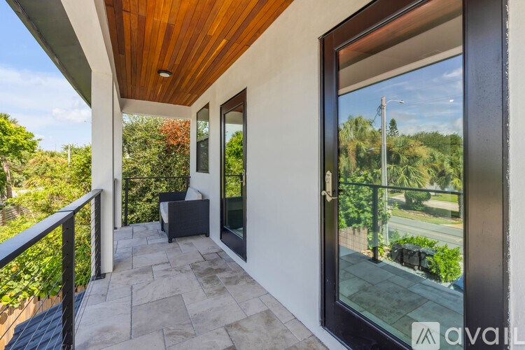 A balcony with a wooden ceiling and a view of a street and trees.