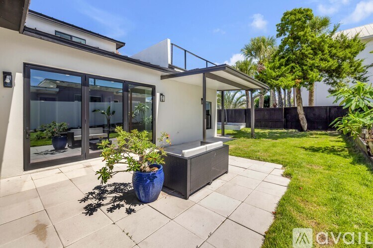 A patio area with a bench, potted plants, and a glass door.