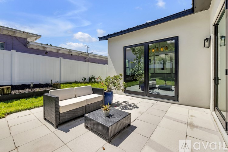 A modern patio with a white couch and a table with a vase of flowers on it.