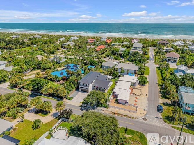 A bird's eye view of a coastal residential area with houses, roads, and a swimming pool.